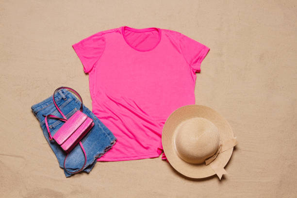 Sand beach texture background. Mockup pink summer t-shirt outfit copy space. Blank template woman shirt Top view. Summertime accessories hat, jeans. Flat-lay closeup tshirt on seashore. Beachtime fondo de textura de playa de arena. maqueta de camiseta rosa de verano copia espacio. plantilla en blanco camisa mujer vista superior. sombrero de accesorios de verano, jeans. camiseta plana de primer plano en la orilla del mar. tiempo de playa