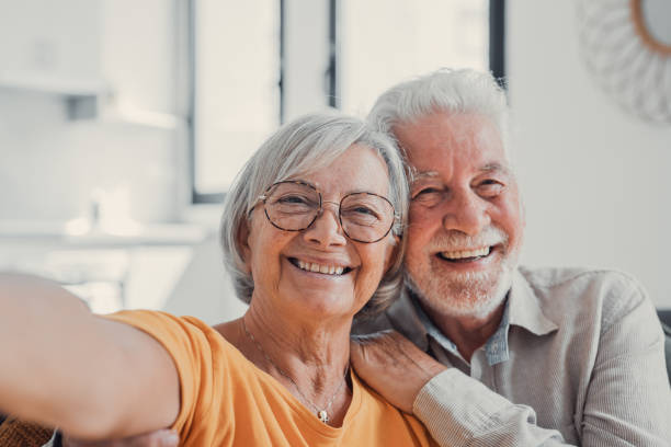 portrait photo heureux couple senior prenant selfie, s’amusant avec la caméra du téléphone, souriant femme âgée et mari étreignant, regardant l’appareil photo, posant pour la photo, homme âgé vlogger enregistrant une vidéo - beautiful indoors looking at camera cheerful photos et images de collection