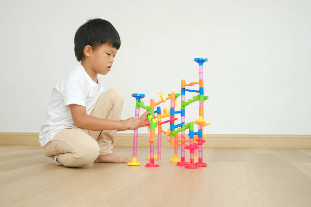 istock Asian boy child sitting on floor having fun playing with colorful plastic Marble Run Track Toy Set 1479377724