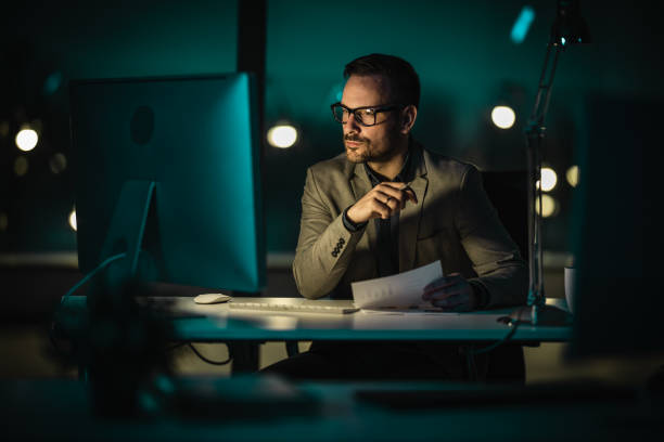 istock Portrait of tired young man working late at night at office with computer 1479378417