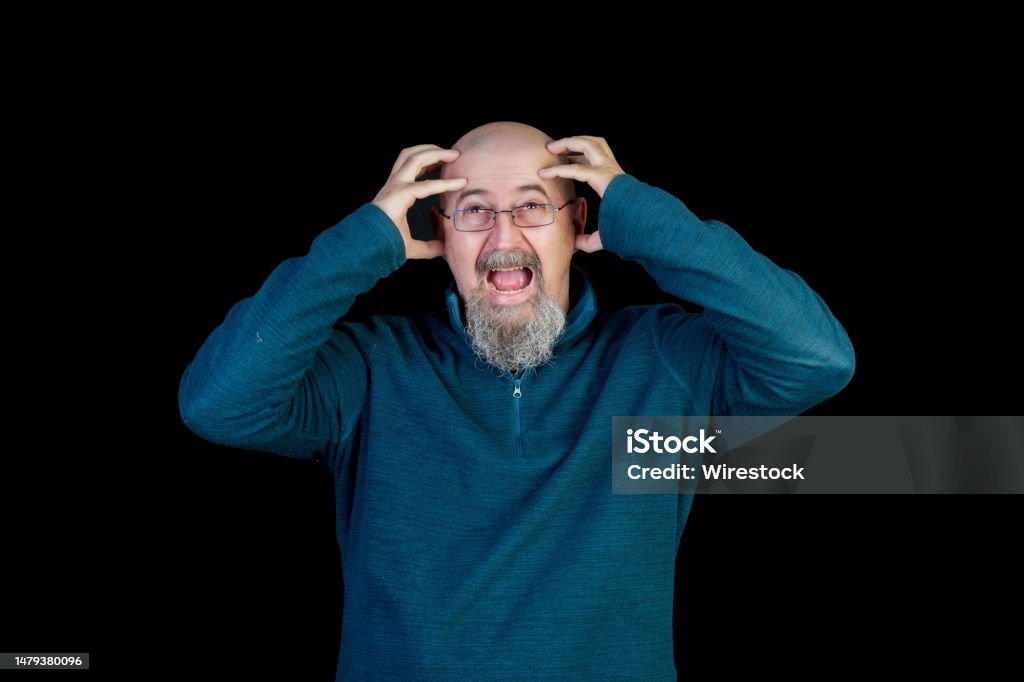 Middle-aged man suffering from a severe headache or migraine, isolated on black background A middle-aged man in a state of discomfort, isolated against a black background, holding his head as if suffering from a severe headache or migraine Adult Stock Photo