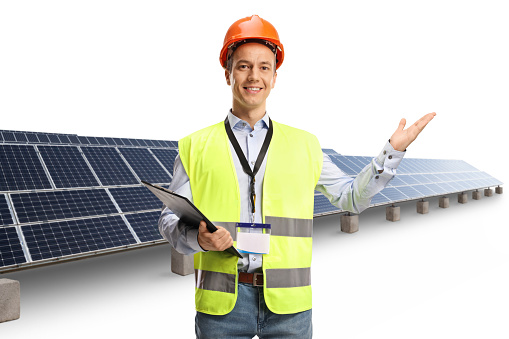 Engineer wearing a reflective vest and helmet and showing a solar panel farm isolated on white background
