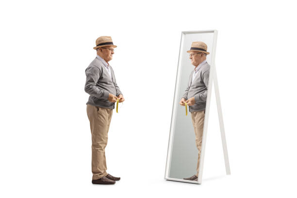 istock Elderly man measuring his waist and looking at a mirror 1479383307