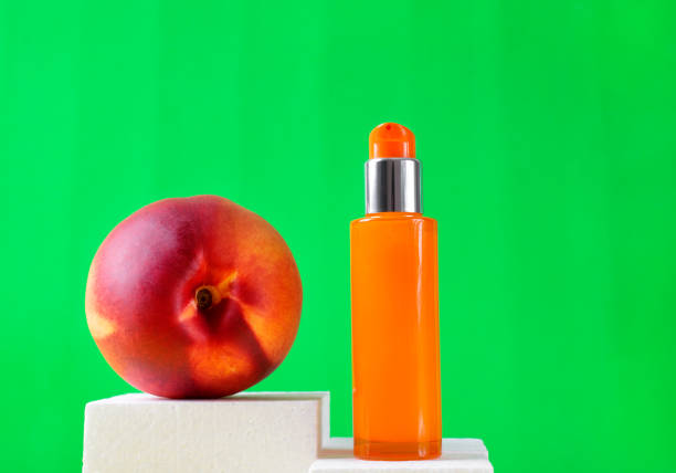 ネクタリン入りスキンケア製品。オレンジ色のディスペンサーボトルと緑の果物 - oil pump ストックフォトと画像