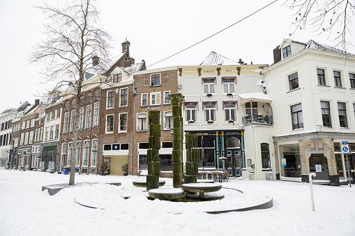 Zutphen, Netherlands – February 08, 2021: Central square with fountain in historic city center of medieval Hanseatic town during a snowstorm