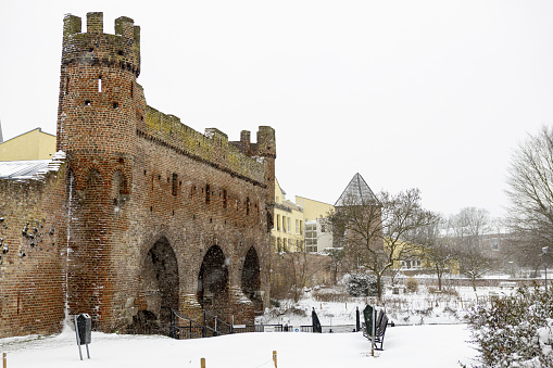 Zutphen, Netherlands – February 08, 2021: Bridge over river Berkel of medieval Hanseatic city during a snowstorm showing remains of the Berkelpoort city wall with the white precipitation