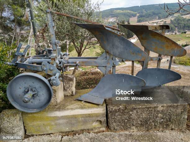 A Steel Plow In The Front Of A House With Trees And Grass Stock Photo - Download Image Now