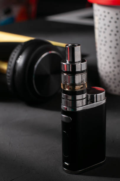 istock Vaping device on the dark surface; the headphones and a plastic coffee cup in the background 1479398242