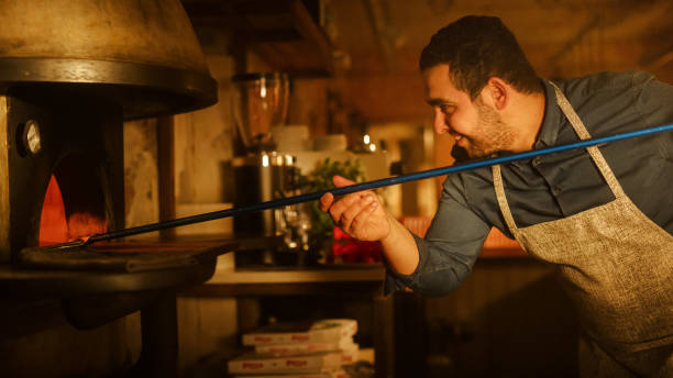 istock In Restaurant Professional Chef Uses Pizza Peel for Transferring Pizza into Wood Fire Stone Oven. Traditional Italian Cooking Family Recipe. Authentic Pizzeria, Delicious Organic Food. Cinematic Shot 1479398979