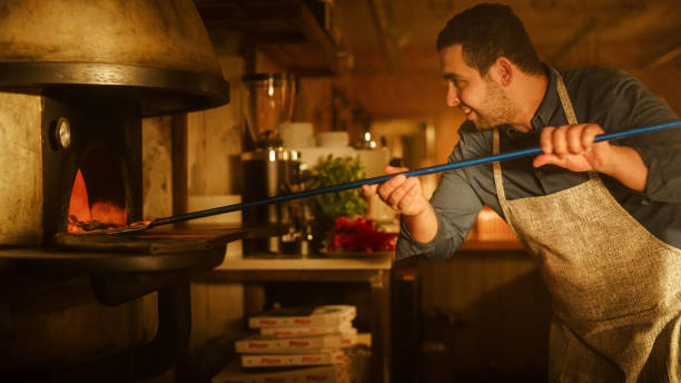 istock In Restaurant Professional Chef Uses Pizza Peel for Transferring Pizza into Wood Fire Stone Oven. Traditional Italian Cooking Family Recipe. Authentic Pizzeria, Delicious Organic Food. Cinematic Shot 1479399010