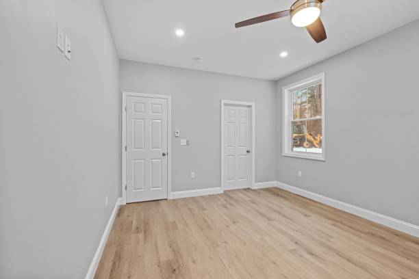 istock Empty room with wood floors and a ceiling fan in front of a window 1479399201