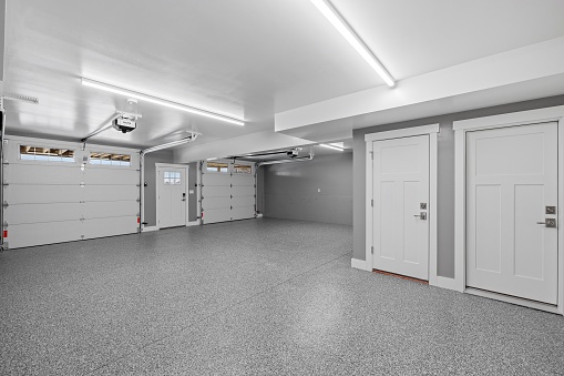 An interior view of an empty garage with a metallic surface floor and lighting