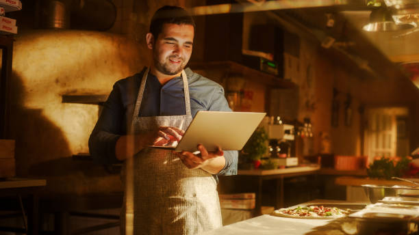 istock In Restaurant: Handsome Male Chef Using Laptop Computer. Authentic Pizza Place Cooking Delicious Organic Eco Food. Bi-racial male Entrepreneur Working on Online Order in Small Business Family Shop 1479399787
