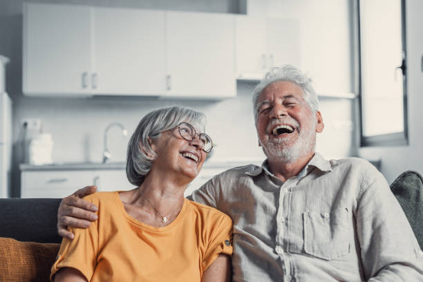 Happy mature husband and wife sit rest on couch at home hugging and cuddling, show care affection, smiling senior loving couple relax on sofa have fun, enjoy tender romantic family weekend together feliz esposo y esposa maduros se sientan descansar en el sofá de casa abrazando y abrazando, muestran afecto de cuidado, sonrientes pareja amorosa mayor relajarse en el sofá divertirse, disfrutar de tierno fin de semana familiar romántico juntos