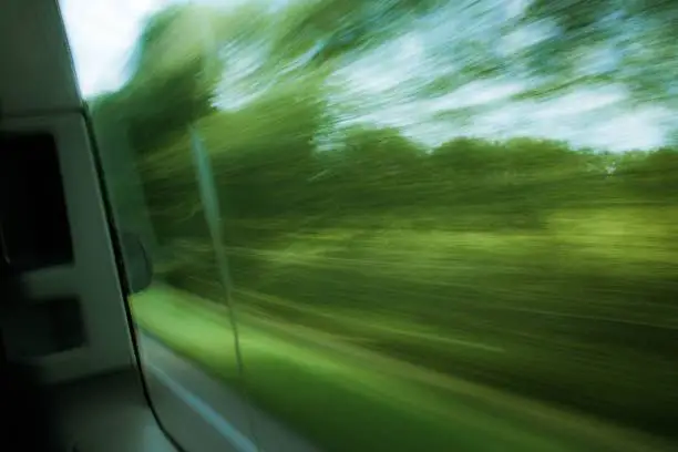 A scenic view of trees seen with a blur effect through the window of a moving vehicle