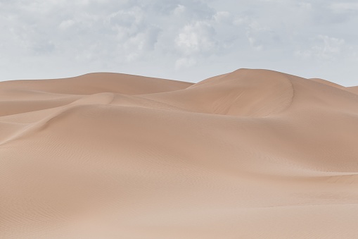 A beautiful view of a deserted area with sand dunes on a cloudy sky background