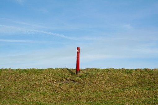 A picturesque view of a grassy meadow with a prominent red pole in the center