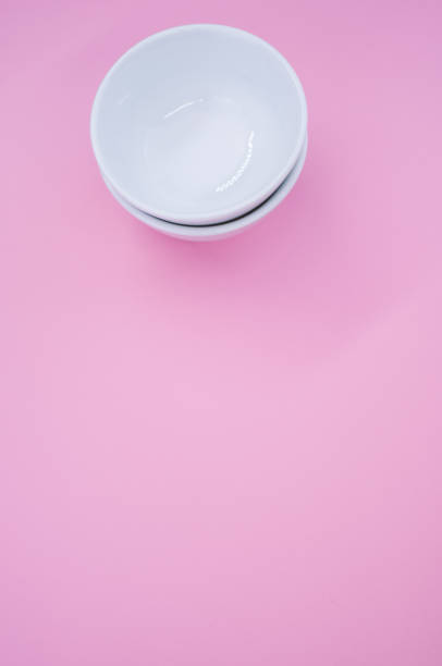 istock Vertical  of two empty white bowls on a pink background with space for your text 1479412534