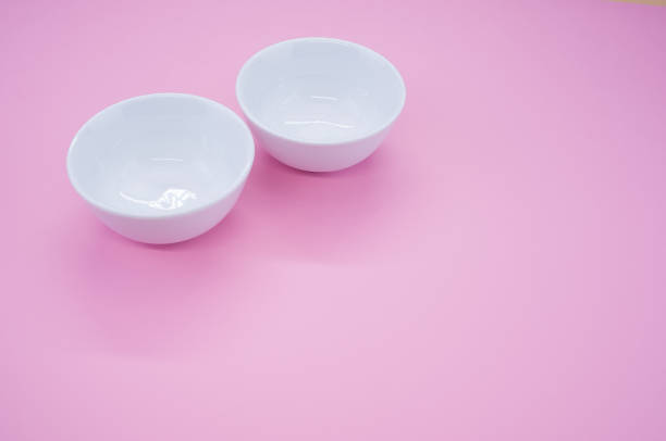 istock Closeup of two empty white bowls on a pink background with space for your text 1479412566
