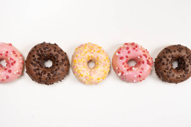 istock Five donuts in a row - white, pink and chocolate on a white background top view 1479417817