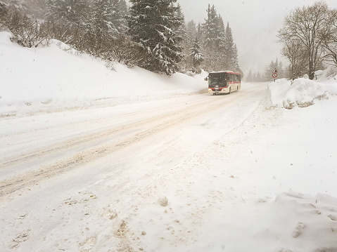 Coach travelling along snow covered roads in Les arcs France during blizzard conditions with beautiful snow covered trees either side of the road.
