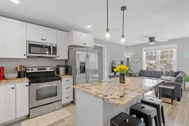 A modern kitchen with white walls and cabinets, featuring stainless steel appliances