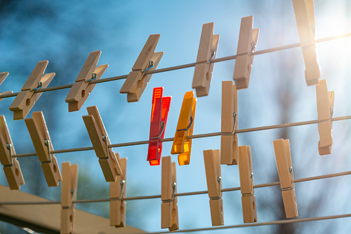 Red, yellow and wooden clothespins on a clothesline on a sunny day, low angle view.