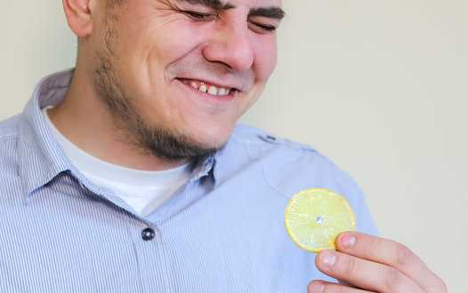 Man eating lemon. Laugh from sour taste.