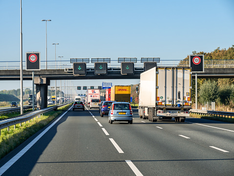 Traffic, speed limit signs and use lane matrix signs with green arrows on motorway A1, Netherlands