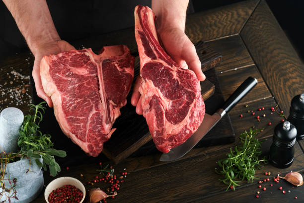 istock Chef cutting steak beef. Mans hands hold raw steak Tomahawk on rustic wooden cutting board on black background. Cooking, recipes and eating concept. Selective focus. 1479423815