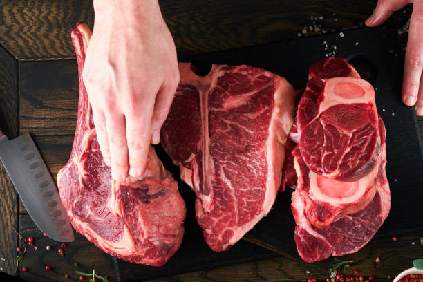 istock Chef cutting steak beef. Mans hands hold raw steak Tomahawk on rustic wooden cutting board on black background. Cooking, recipes and eating concept. Selective focus. 1479423816
