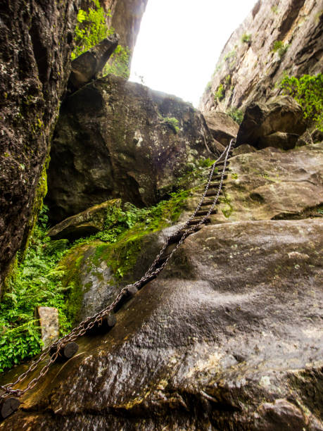 Way up along a precarious chain ladder. This chain ladder is going up a wet rock in the Crack, one of the hiking routes in the Royal Natal National Park in South Africa.