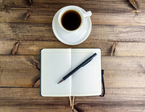 istock Coffee in a cup and a notepad with a pen, top view. 1479424863