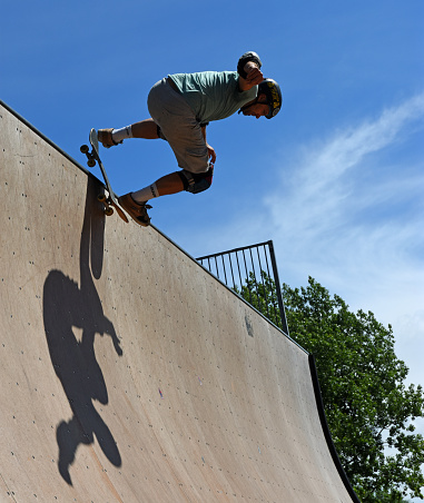St Neots, Cambridgeshire, England - July 03, 2022: Skateboarder performing stunt on Vert Ramp.