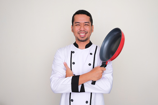 Asian Chef smiling confident with arms crossed and holding a frying pan