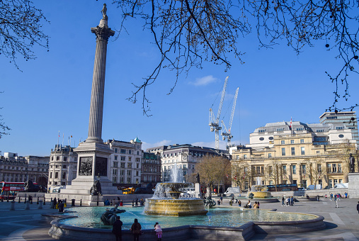 London, UK - April 3 2023: Daytime view of Nelson's Column and a fountain in Trafalgar Square with a clear blue sky.