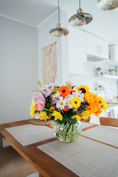 istock Kitchen counter table with focus on vase with huge multicolor various flower bouquet with blurred background of modern cozy white kitchen. Home interior design details. Mother's day. Copy space. 1479427724