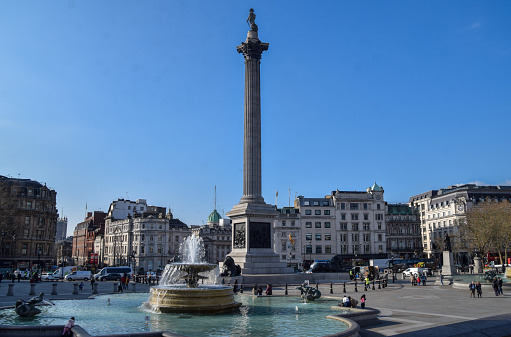 London, UK - April 3 2023: Daytime view of Nelson's Column and a fountain in Trafalgar Square with a clear blue sky.