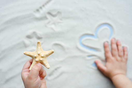 Child plays with sand, draws a heart.