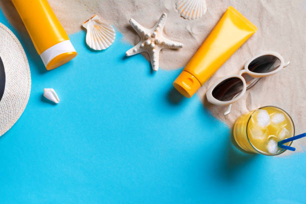 Summer beach background Summer beach composition with sunblock lotion bottles, starfish, sea shells, cocktail on blue background with sand, copy space. Summer vacation and beach relax concept template. shell starfish orange sea stock pictures, royalty-free photos & images