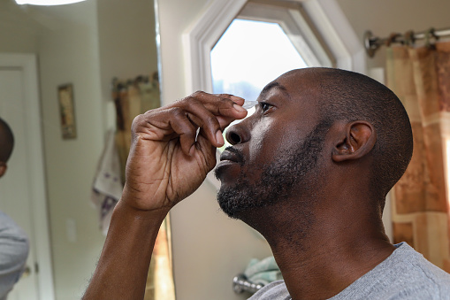 A portrait of a black man using eye drops