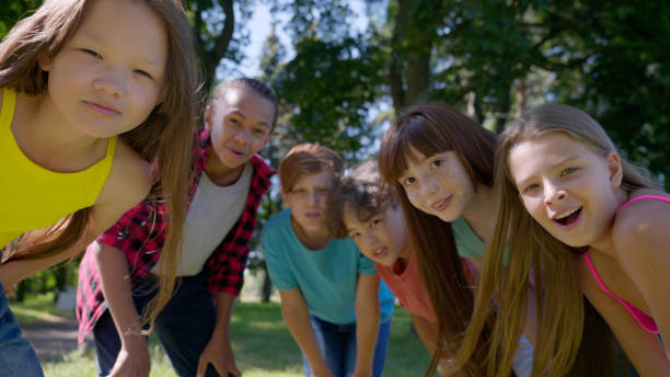 istock Multiethnic kids bending and looking at camera outdoors in park 1479437020