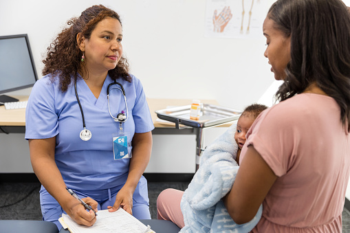 The mature adult female OB/GYN listens empathetically to the depressed young adult mother.