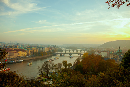 landscape with Vltava river, Charles Bridge and boat at sunset in autumn in Prague, Czech Republic.