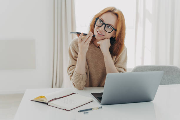 istock female freelancer records voice message sits at desktop makes notes in notepad 1479441031