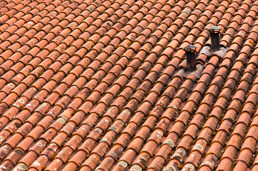 Red clay tile rooftop and two small chimneys, full frame view. Allariz , Ourense province, Galicia, Spain.