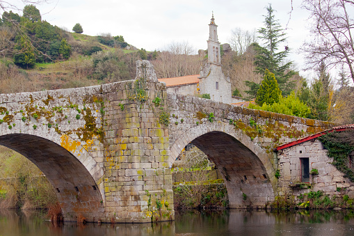 Allariz ancient Vilanova stone bridge over Arnoia river, set in XIII century and Santa María de Vilanova church,  old town Allariz , Ourense province, Galicia, Spain.