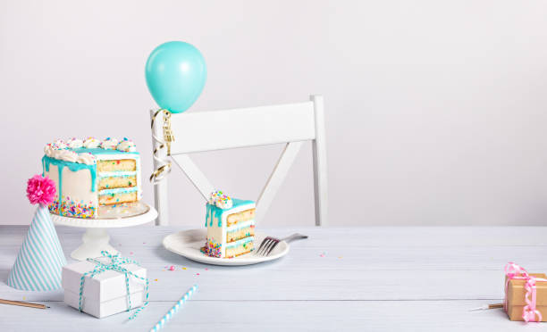 Birthday party setting with slice of cake and decorations on a light grey white background
