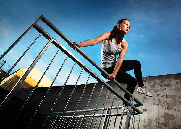 Woman jumping over fence obstacles Young woman jumping over fence obstacles while doing Parkour in an urban area.  free running stock pictures, royalty-free photos & images