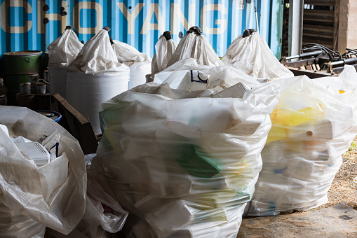 A shot of recycling bags ready to be collected from the farm. Empty plastic container bottles are used for agricultural farming to store chemicals. The plastics have been collected and stored to be recycled after use.